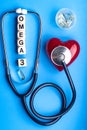 fish oil and stethoscope, vitamins for health, omega 3, pill yellow color and red heart on blue background. The inscription on