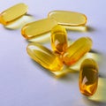 Fish oil. Yellow softgels or capsules lie on violet surface. Square illustration about vitamins and healthy lifestyle. Softgel