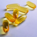 Fish oil. Yellow softgels or capsules lie on violet surface. Square illustration about vitamins and healthy lifestyle. Softgel