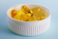 Fish oil. Yellow softgels or capsules are in white bottle cap. Light blue surface. Vitamins and healthy lifestyle. Illustration