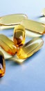 Fish oil. Yellow softgels lie on a light blue surface. Healthy lifestyle. Vertical illustration. Softgel closeup. Omega-3 fatty