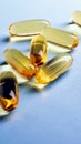 Fish oil. Yellow softgels lie on a light blue surface. Healthy lifestyle. Vertical stories. Softgel closeup. Omega-3 fatty acids