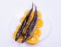 Fish on orange slices laid out on a white plate Royalty Free Stock Photo