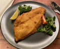 Fish plaice fillet with lemon on wooden table.