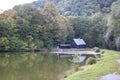 Fish pond surrounded by trees and old cottage