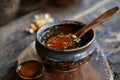 Fish sauce garum in a deep bowl with a spoon with spices on a wooden table.