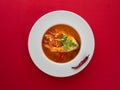 Fish soup in white plate with chilli pepper on red background. Overhead view Royalty Free Stock Photo