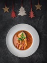 Fish soup in white plate and christmas decoration. Dark background. Overhead Royalty Free Stock Photo