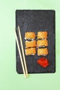 Fish sushi rolls with salmon, wasabi and chopsticks on black cutting serving board on green background with copy space. Seafood, Royalty Free Stock Photo