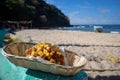 A fish taco in a basket sitting on the edge of a boat on the beach