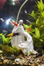 A fish tank decorated wiha a Christmas statuette.