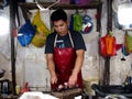 A fish vendor cuts up and cleans fresh fishes which she sells at a fish port and public market