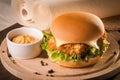 Fishburger with fresh salad and cheese on round wooden board