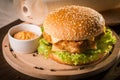 Fishburger with fresh salad and cheese on round wooden board Royalty Free Stock Photo