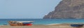 Fisher boats at the turtle beach of Sao Pedro on Sao Vicente Island, background the lighthouse Royalty Free Stock Photo