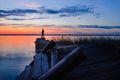 Fisher on evening old pier on the lake at sunset Royalty Free Stock Photo