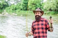 Fisher fishing equipment. Rest and recreation. Fish on hook. Brutal man stand in river water. Man bearded fisher. Fisher