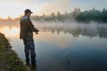 Fisher fishing on foggy sunrise Royalty Free Stock Photo