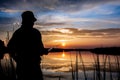 Fisher man fishing on a lake bank at sunset Royalty Free Stock Photo