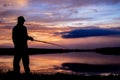 Fisher man fishing on a lake bank at sunset Royalty Free Stock Photo