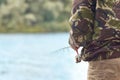 Fisher man fishing with spinning rod on a river bank against background of water in blur Royalty Free Stock Photo