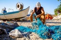 Fisher piles up and cleans fishing net at sandy beach