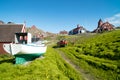 Fisherboat Sisimiut, Greenland. Colorful wooden boat on green summer meadow with wooden colorful houses