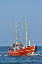 A fisherboat with people in the baltic sea, followed by seagulls