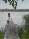 Fisherman back on old wood pier over lake water in summer Royalty Free Stock Photo