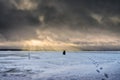 Fisherman on a background of storm clouds. Winter ice fishing on the lake Royalty Free Stock Photo