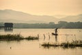 fisherman at bang phra reservoir catch fish by wood stick at sunrise Royalty Free Stock Photo