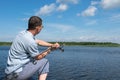 A fisherman on the bank fishes on a spinning on the river against the blue sky Royalty Free Stock Photo