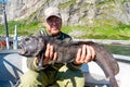 Fisherman with big wolffish near Lofoten, Senija, Alta Norway. Man holding catch Atlantic wolf fish Royalty Free Stock Photo