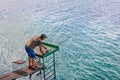 A fisherman is fishing by spinning on the river bank, standing on a wooden platform Royalty Free Stock Photo