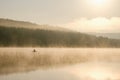 A fisherman in a boat catches fish in the early foggy morning Royalty Free Stock Photo