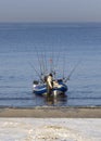Fisherman with a boat and fishing rods on the shore of the Baltic Sea on a sunny day in the city of Klaipeda, Lithuania