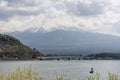 Fisherman on a boat on Lake Kawaguchi with Mount Fuji in the background covered with snow and veiled by clouds, Japan Royalty Free Stock Photo