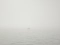 Fisherman in a boat on a lake in a thick fog catches fish with a fishing rod Royalty Free Stock Photo