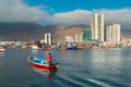 Fisherman in a boat at the marina of Iquique with city skyline inthe back