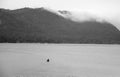 A fisherman on a boat in the middle of a mountain lake during the rain. Black and white photo Royalty Free Stock Photo