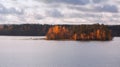 Fisherman in a boat near a small island on the lake. Autumn forest, distant panorama Royalty Free Stock Photo