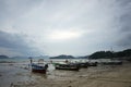 Fisherman boat parking on the lower tide beach with the dull sky