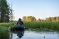 Fisherman in a boat prepares to fish, in a channel between lakes, at dawn, against the background of the forest and the Royalty Free Stock Photo