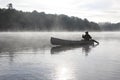 Fisherman Canoeing on a Misty Lake Royalty Free Stock Photo