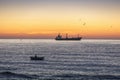 Fisherman and cargo ship sailing in the sea on sunrise Royalty Free Stock Photo