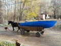 A fisherman carries his blue boat, with the cart