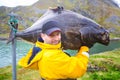 fisherman carries on his shoulder a huge fish. 25 kg halibut.