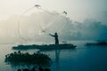 Fisherman casting out his fishing net in the river.