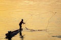 Local fisherman casts his net from a small boat at sunset,on the Mekong river,in southern Laos