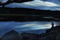 Fisherman catches fish at dusk on a break of river in forest. Dark gloomy photo. USA. Maine. fishing in the USA.